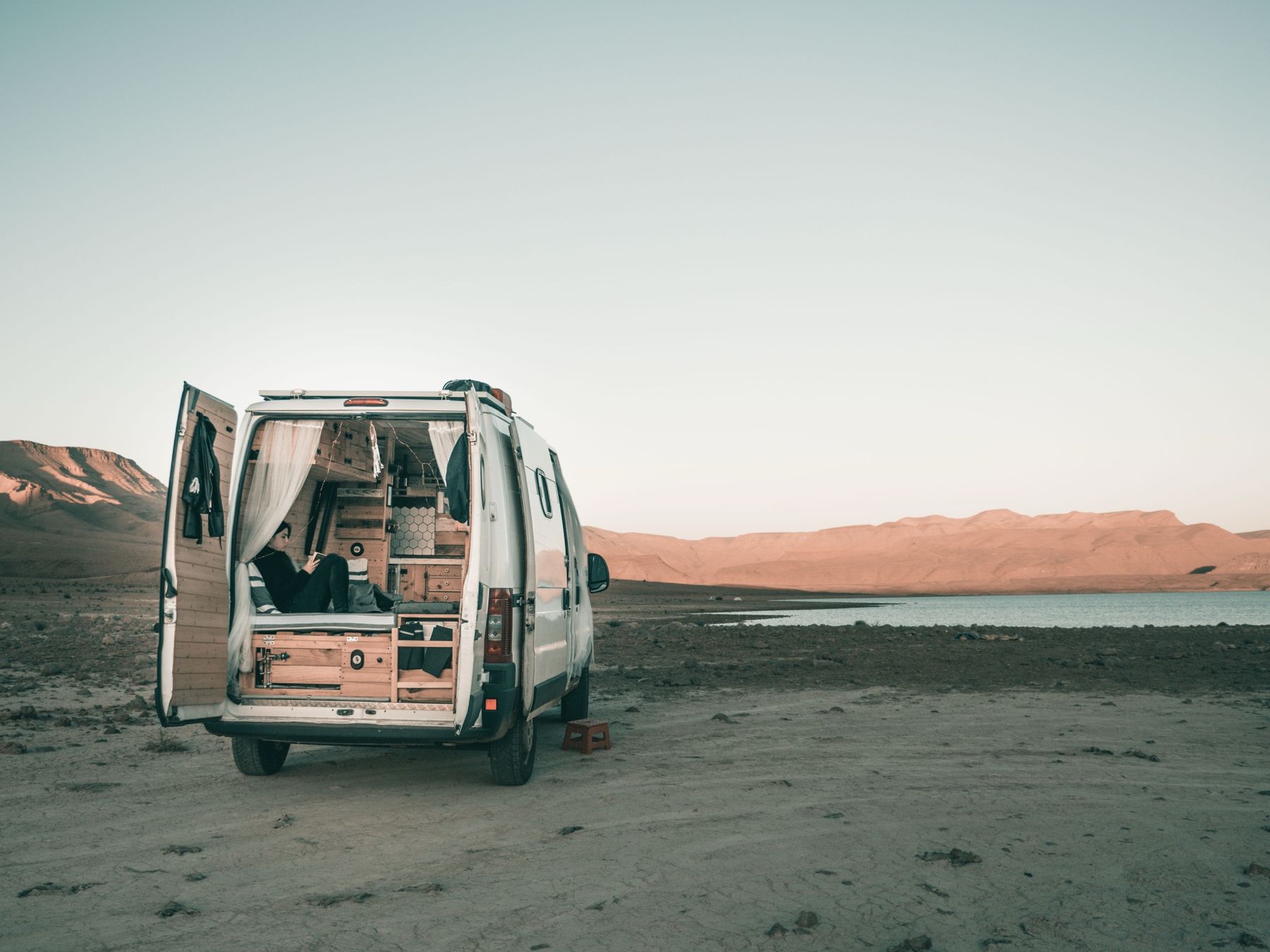 Nuestra furgoneta camper con las puertas abiertas frente a un lago en Marruecos